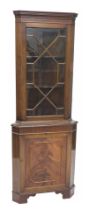 A mahogany standing corner cabinet with a single glazed door and a panel door on bracket feet.