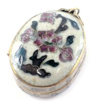 An early 20thC enamel and brass oval locket, on a cream floral design with gilded decoration, 3cm hi