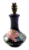 A Moorcroft pottery table lamp, on a royal blue ground with pink flower decoration, cable cut, 25cm