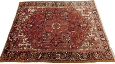 A Persian Heriz carpet, with a design of medallions, flowers, etc., in predominantly red on a cream