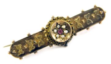 An Edwardian 9ct gold bar brooch, with raised leaf decoration set with garnet and seed pearls, 4cm w