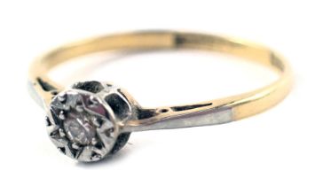 A diamond solitaire dress ring, the illusion set tiny diamond in a rub over setting, on yellow metal