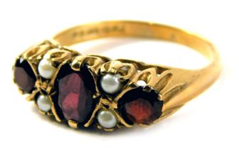 A 9ct gold gypsy ring, set with an oval garnet and two round brilliant cut garnets and four cultured