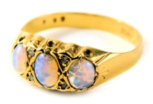 An opal dress ring, set with three oval opals and two tiny diamonds, in a raised claw setting on yel