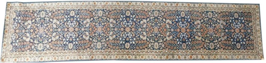 A Persian style runner, with a design of flowers, on a navy blue ground, one wide and various narrow