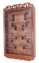 A Chinese hardwood wall cabinet, with a pierced crest above a glazed panel enclosing various shelves
