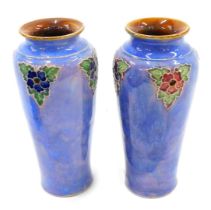A pair of Royal Doulton stoneware vases, each decorate with flowers and leaves, on a mottled purple