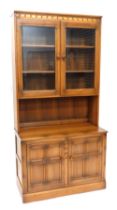 An Ercol mid coloured elm room unit or dresser, with two glazed doors, the base with two panelled do