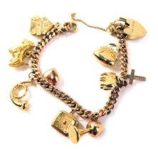 A 9ct gold curb link bracelet, set with nine charms, to include spotty dog, house, goblet and others