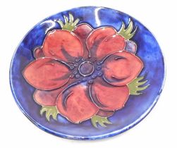 A Moorcroft Pink Pansy pattern pin dish, on a Royal blue ground with pink flowers, 12cm diameter.