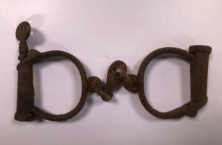 A pair of WWII cast and wrought iron handcuffs, with key.