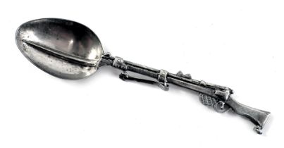 A novelty rifle teaspoon, the handle formed as a rifle, white metal unmarked, 10cm wide.