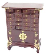 A Chinese small hardwood cabinet, with brass mounts and arrangement of twenty drawers and two doors,
