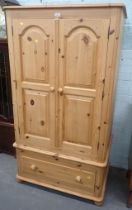 A pine two door wardrobe with drawer to base.