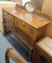 An oak sideboard, with mirrored back, above arrangement of two drawers and single cupboard, on twist