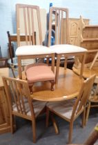 A modern beech effect circular kitchen table and four chairs, and a footstool. The upholstery in th