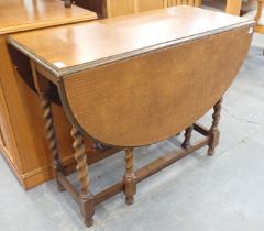 A mahogany drop leaf table on barley twist column supports.