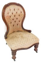 A Victorian mahogany spoon back nursing chair, upholstered in button back and over stuffed floral fa
