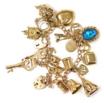 A 9ct gold curb link charm bracelet, with nineteen charms as fitted, on two heart shaped padlock cla