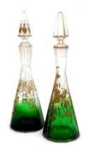 A pair of late 19thC continental glass decanters, of faceted outswept form, gilt decorated with vine