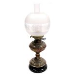 An early 20thC duplex copper oil lamp, with embossed foliate decoration, on a socle base, glass chim