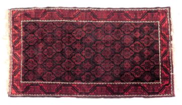 A Caucasian blue and red ground rug, with a central field of repeating medallions, within repeating