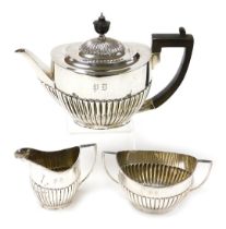 An Edward VII silver three piece tea service, of semi fluted form, monogram engraved, comprising tea