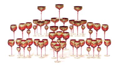 A mid 20thC Venetian ruby glass suite of table glassware, over decorated in enamel with flowers, gil