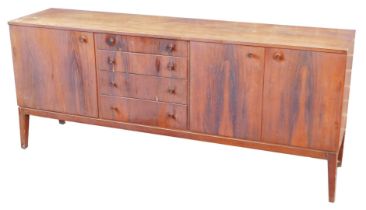 A mid century rosewood sideboard, having four central graduated drawers, flanked by a cupboard door