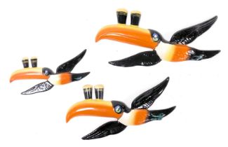 A set of three Carltonware graduated flying Guinness Toucan wall plaques, the pair of glasses painte