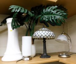 A plant stand with planter, a Tiffany style lamp and two other lamps.