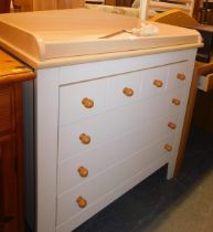 A modern beech finish changing table, with a shaped top above arrangement of four long drawers, and