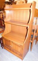 An Ercol elm waterfall bookcase, above a pair of panelled doors, raised on a plinth base, 113cm high