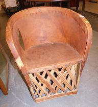 A tribal style tub chair, with basket weave design, hide tub seat and shaped base, partially studded