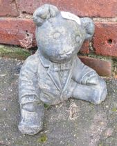 A reconstituted stone garden ornament of a seated teddy bear.