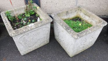 A pair of reconstituted stone garden planters, decorated with hogs and flowers, of square form.