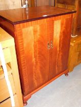 A mahogany veneered and inlaid two door cupboard, raised on short cabriole supports.