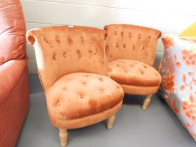 A pair of blush upholstered buttoned back and button seated lounge chairs, on turned legs. This lot