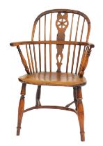 An early 19thC yew and elm wheel back Windsor chair, with a solid saddle seat, raised on turned legs