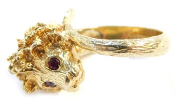 A 9ct gold dress ring, in the form of a cast lion's head with ruby eyes, the shank formed by a tail,