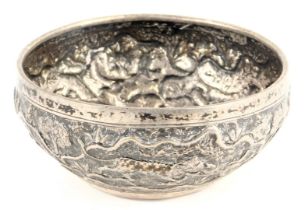 An Indian white metal bowl, repousse decorated with various animals, to include a tiger attacking an