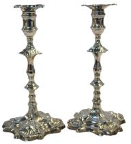 A pair of silver taper sticks, probably 18thC, of leaf embossed and turned form, raised on a small c