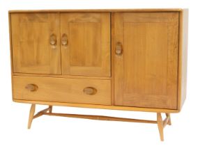 An Ercol light elm sideboard, with a pair of doors opening to reveal a single shelf, over a frieze d