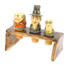 A set of three Allan Young Pottery wine stoppers, each depicting a male, one in a black hat, on a po