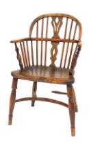 An early 19thC oak and elm Windsor chair, with a carved splat, solid saddle seat, raised on turned l