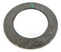 An Arts and Crafts pewter framed wall mirror, of circular form, the top inset with a green enamelled