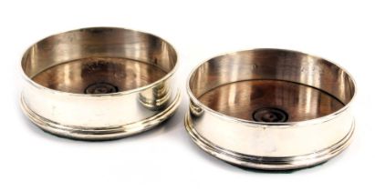 A pair of Elizabeth II silver wine coasters, each with a turned hardwood base, London 1983, 12.5cm d