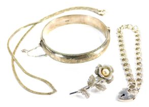 A silver hinged bangle and a chain link bracelet, the bangle with engraved decoration, the bracelet