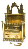 A Victorian brass miniature chest of drawers, with a raised shaped back, the base over two short and