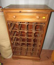 A pine wine rack, the top with a moulded edge above a drawer, the base with an arrangement of recess